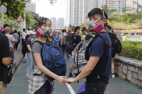 A couple hold hands as they join a protest in Hong Kong on Monday, Aug. 5, 2019. Droves of protesters filled public parks and squares in several Hong Kong districts on Monday in a general strike staged on a weekday to draw more attention to their demands that the semi-autonomous Chinese city's leader resign.(AP Photo/Kin Cheung)