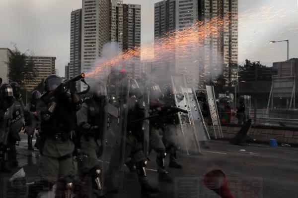 A riot police fires tear gas during a confrontation with protesters on Monday, Aug. 5, 2019. Droves of protesters filled public parks and squares in several Hong Kong districts on Monday in a general strike staged on a weekday to draw more attention to their demands that the semi-autonomous Chinese city's leader resign.(AP Photo/Kin Cheung)
