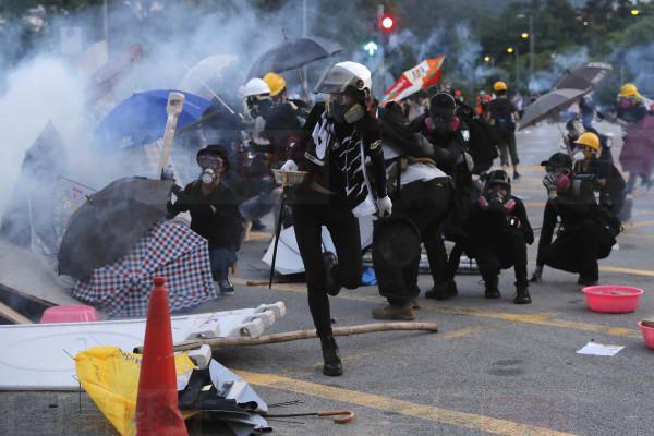 Protesters huddle during a confrontation with police in Hong Kong Monday, Aug. 5, 2019. Droves of protesters filled public parks and squares in several Hong Kong districts on Monday in a general strike staged on a weekday to draw more attention to their demands that the semi-autonomous Chinese city's leader resign.(AP Photo/Kin Cheung)