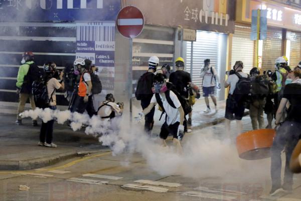 Protesters react to tear gas during a confrontation with police in Hong Kong on Saturday, Aug. 10, 2019. Hong Kong is in its ninth week of demonstrations that began in response to a proposed extradition law but have expanded to include other grievances and demands for more democratic freedoms.(AP Photo/Kin Cheung)