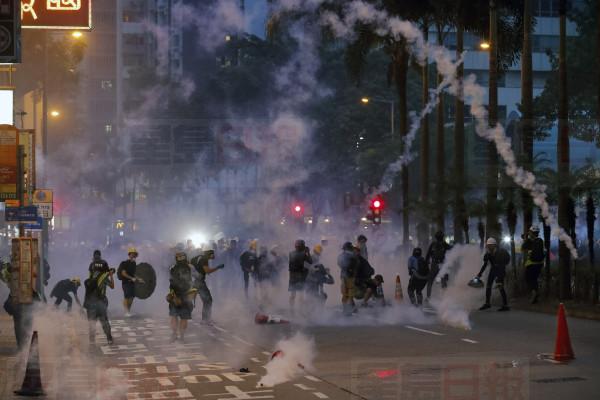 Protesters react with tear gas canisters fired by riot policemen on a street in Hong Kong, Sunday, Aug. 11, 2019. Police fired tear gas late Sunday afternoon to try to disperse a demonstration in Hong Kong as protesters took over streets in two parts of the Asian financial capital, blocking traffic and setting up another night of likely showdowns with riot police. (AP Photo/Vincent Thian)