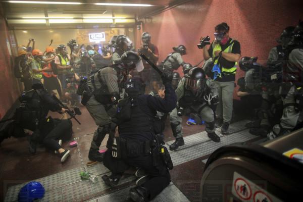 Policemen charge and arrest protesters inside the Tai Koo MTR station during the anti-extradition bill protest in Hong Kong, Sunday, Aug. 11, 2019. Police fired tear gas Sunday inside a train station and in several other Hong Kong neighborhoods where protesters occupied roads in another weekend of anti-government demonstrations. (Jeff Cheng/HK01 via AP)