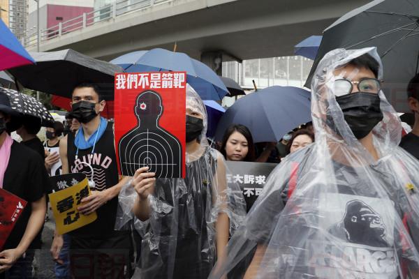 Protesters, some wearing eye patches to show solidarity to a woman reportedly injured in the eye by a beanbag fired by police, hold up a banner which reads "We are not targets" in Hong Kong on Sunday, Aug. 18, 2019. A spokesman for China's ceremonial legislature condemned statements from U.S. lawmakers supportive of Hong Kong's pro-democracy movement, as more protests were planned Sunday following a day of dueling rallies that highlighted the political divide in the Chinese territory. (AP Photo/Kin Cheung)