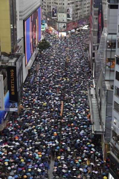Demonstrators carry umbrellas as they march along a street in Hong Kong, Sunday, Aug. 18, 2019. Heavy rain fell on tens of thousands of umbrella-ready protesters Sunday as they started marching from a packed park in central Hong Kong, where mass pro-democracy demonstrations have become a regular weekend activity. (AP Photo/Vincent Yu)