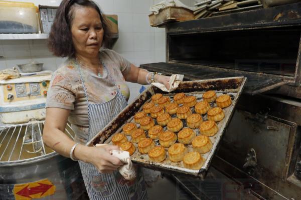 In this Friday, Aug. 9, 2019 photo, a staff member holds a tray of mooncakes with Chinese words "Hong Kong people" at Wah Yee Tang bakery in Hong Kong. A Hong Kong bakery is doing its part to support the citys pro-democracy protest movement by making mooncakes with a message. At Wah Yee Tang, the traditional Chinese harvest festival treat comes with a twist: slogans opposing the citys Beijing-backed government and promoting Hong Kongs unique identity that have become popular rallying cries since the protests began two months ago. (AP Photo/Kin Cheung)