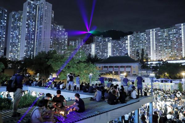 People gather in Wong Tai Sin district as demonstrators hold up laser pointers on the Lion Rock mountain in the background in Hong Kong, Friday, Sept. 13, 2019. Thousands of Hong Kong people carried lanterns with pro-democracy messages and formed human chains on two of the city's mountain peaks during mid-autumn festival celebrations Friday night, sustaining months-long protests for democratic reforms in the semi-autonomous Chinese territory. (AP Photo/Kin Cheung)