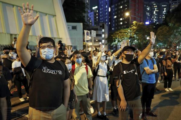 Protesters gesture as they gather outside the Queen Elizabeth Stadium in Hong Kong, Thursday, Sept. 26, 2019. Riot police on Thursday begun securing a stadium in downtown Hong Kong ahead of a town hall session by embattled city leader Carrie Lam, aimed at cooling down months of protests for greater democracy in the semi-autonomous Chinese territory. (AP Photo/Vincent Thian)