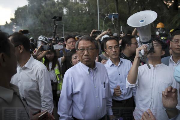 Professor Rocky Tuan, the president of the Chinese University, center, arrives to negotiate with the students and police after a clash on the campus of Chinese University in Hong Kong, Tuesday, Nov. 12, 2019. Police fired tear gas at protesters who littered streets with bricks and disrupted morning commutes and lunch breaks Tuesday after an especially violent day in Hong Kong's five months of anti-government demonstrations. (AP Photo/Kin Cheung)