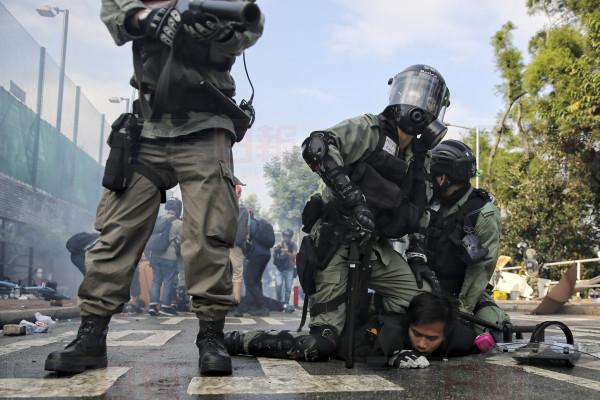 Riot police detained a student during clashes at the Chinese University in Hong Kong, Tuesday, Nov. 12, 2019. Police and protesters have battled outside university campuses and several thousand demonstrators blocked roads as they took over a central business district at lunchtime in another day of protest in Hong Kong. (Steve Leung/HK01 via AP)