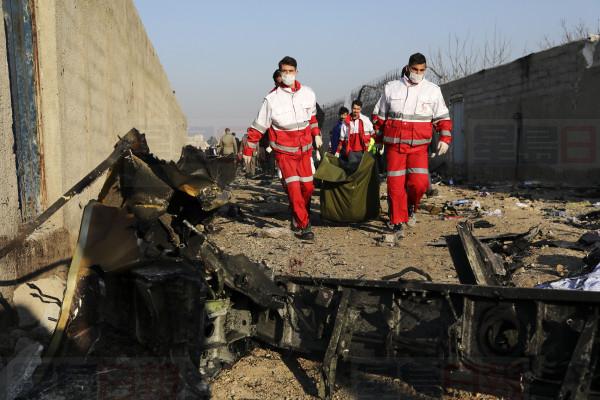 Rescue workers carry the body of a victim of an Ukrainian plane crash among debris of the plane in Shahedshahr, southwest of the capital Tehran, Iran, Wednesday, Jan. 8, 2020. A Ukrainian airplane carrying 176 people crashed on Wednesday shortly after takeoff from Tehran's main airport, killing all onboard. (AP Photo/Ebrahim Noroozi)