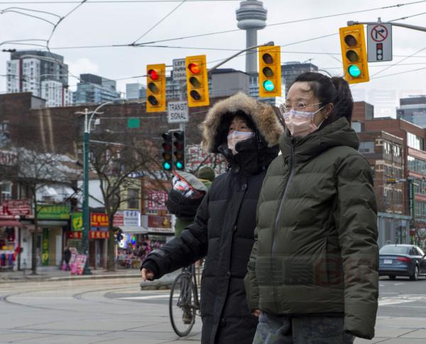 Pedestrians wear protective masks as they walk in Toronto on Monday, January 27, 2020. Canada's first presumptive case of the novel coronavirus has been officially confirmed, Ontario health officials said Monday as they announced the patient's wife has also contracted the illness. THE CANADIAN PRESS/Frank Gunn