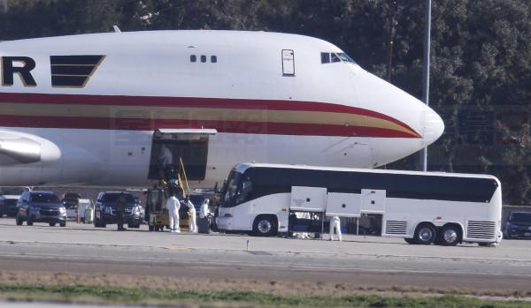 Personnel in protective clothing unload luggages from the airplane carrying U.S. citizens being evacuated from Wuhan, China, at March Air Reserve Base in Riverside, Calif. Jan. 29, 2020.  The passengers will undergo additional screenings in California and be placed in temporary housing. Officials have not said how long they will stay there.  (AP Photo/Ringo H.W. Chiu)
