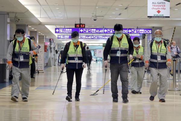 Masked workers disinfect a passenger throughfare at the Taoyuan International Airport on Jan. 22, 2020, after Taiwan reported its first case of the new virus a day earlier.