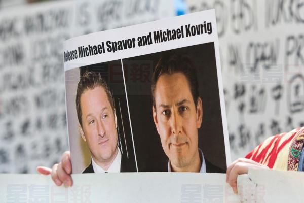 A demonstrator holds an image of Michael Spavor, left, and Michael Kovrig. China on Friday charged the two Canadians with espionage offences.