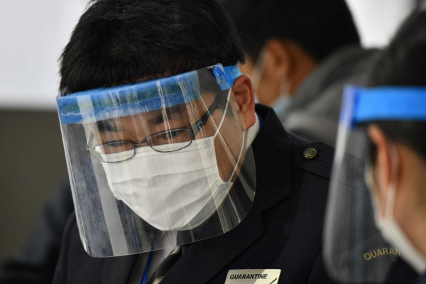 An officer wearing a face mask and shield works at a quarantine station at Narita airport, Chiba prefecture on March 9, 2020. - Japanese Prime Minister Shinzo Abe on March 5 announced that foreign arrivals who have recently been in China or South Korea would be required to spend 14 days in quarantine amid concerns of the COVID-19 novel coronavirus. (Photo by Kazuhiro NOGI / AFP)