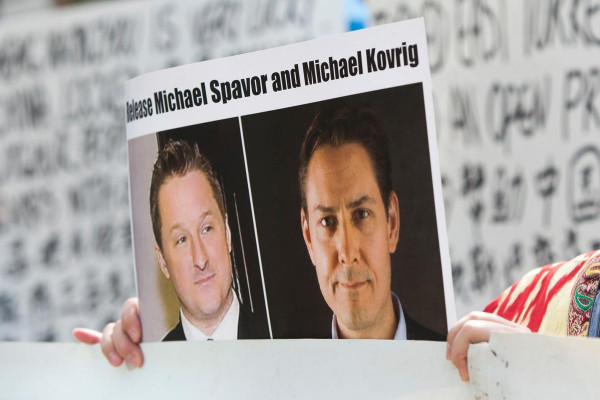 A demonstrator holds an image of Michael Spavor, left, and Michael Kovrig. China on Friday charged the two Canadians with espionage offences.