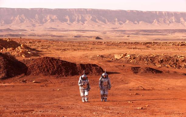 TOPSHOT - A couple of astronauts from a team from Europe and Israel walk in spacesuits during a training mission for planet Mars at a site that simulates an off-site station at the Ramon Crater in Mitzpe Ramon in Israel's southern Negev desert on October 10, 2021. - Six astronauts from Portugal, Spain, Germany, the Netherlands, Austria, and Israel will be cut off from the world for a month, from October 4-31, only able leave their habitat in spacesuits as if they were on Mars. Their mission, the AMADEE-20 Mars simulation, will be carried out in a Martian terrestrial analog and directed by a dedicated Mission Support Center in Austria, to conduct experiments ahead of future human and robotic Mars exploration missions. (Photo by JACK GUEZ / AFP) (Photo by JACK GUEZ/AFP via Getty Images)