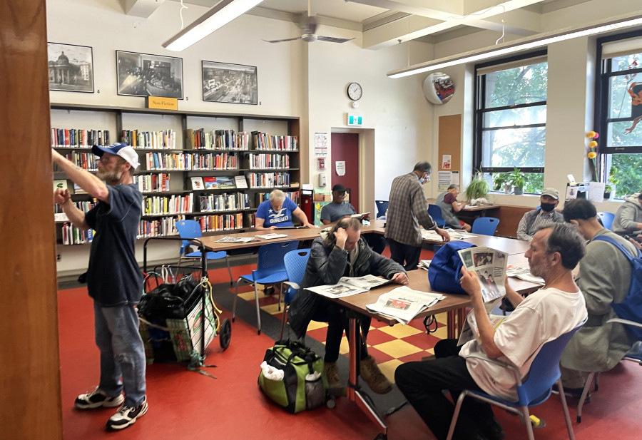 社區中心圖書館內閱讀報紙書籍的避暑居民