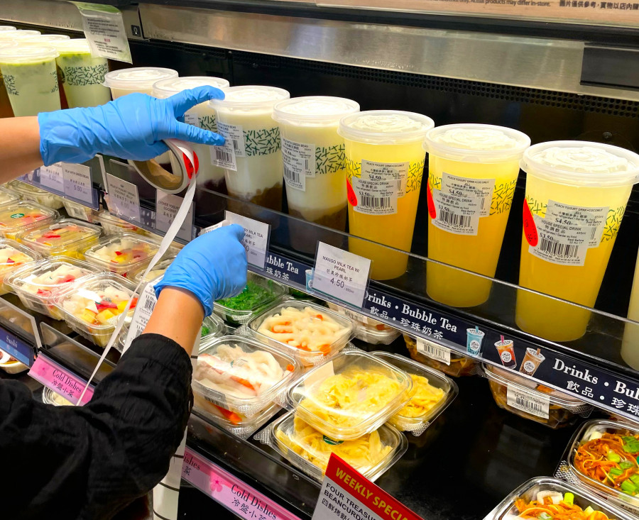 超市員工在7時左右開始為無法過夜存放的食品貼上減價標識。星島記者王弘樹攝