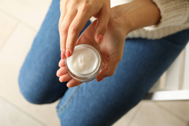 Woman in sweater and jeans hold jar of cosmetic cream