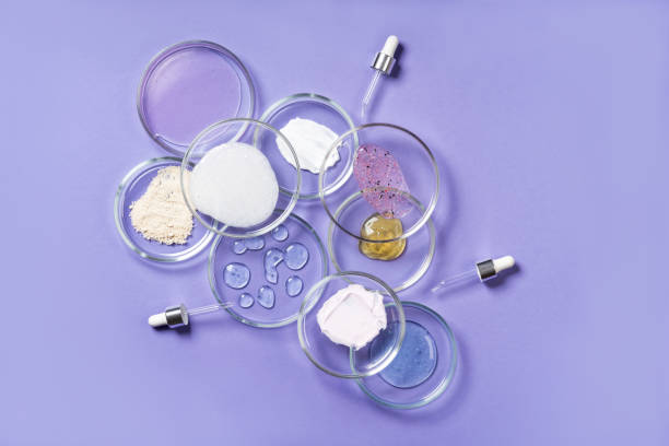 Cosmetic products, scrub, face serum and gel in many petri dishes on a pink background. Cosmetics laboratory research concept