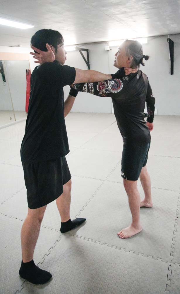 稍為踏前,然後從他的手臂內側伸手抓著他的後頸;